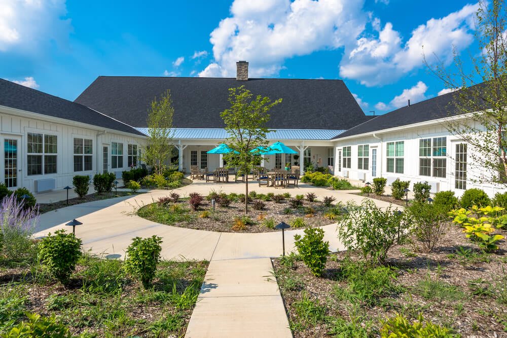 A beautiful residential courtyard with a central garden and surrounding pathways, set under a bright blue sky.