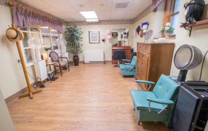 A cozy salon waiting area with vintage chairs, wooden flooring, and decorative elements.