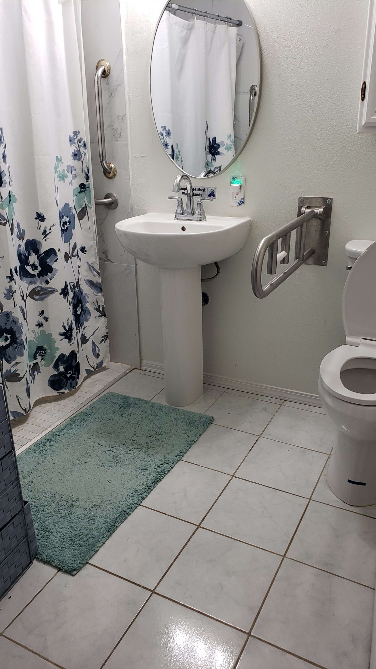 A clean bathroom with a floral shower curtain, white sink, and toilet.