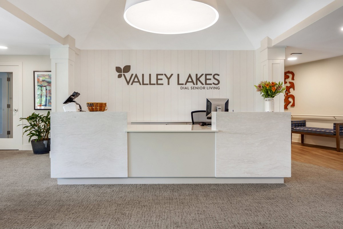 A modern reception area at Valley Lakes with a welcoming desk and floral decor.
