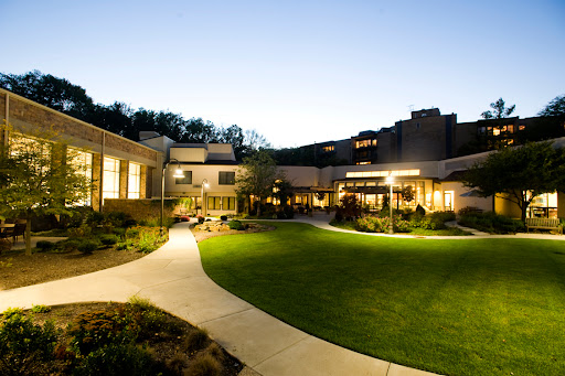 A serene view of a modern building complex during twilight, featuring well-lit pathways and green lawns.