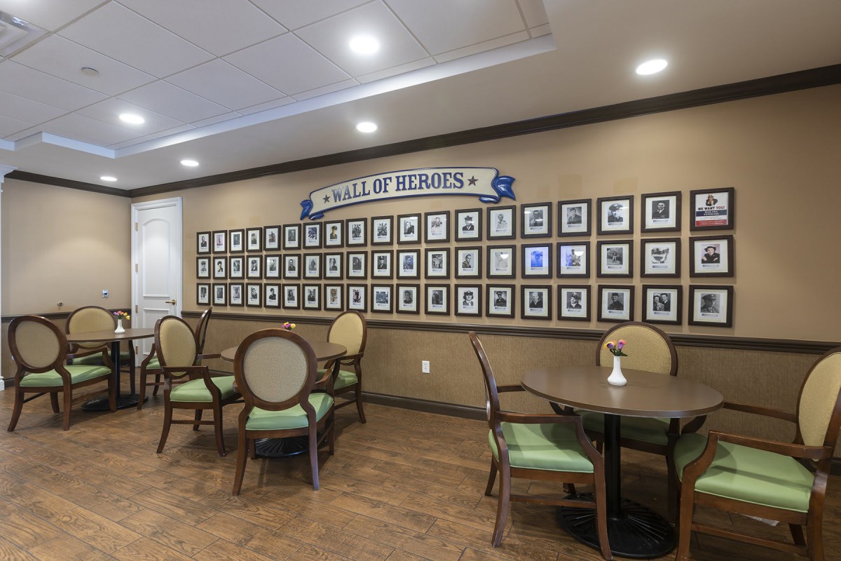 An interior space featuring a 'Hall of Honor' photo wall with seating arrangements, including tables and chairs.