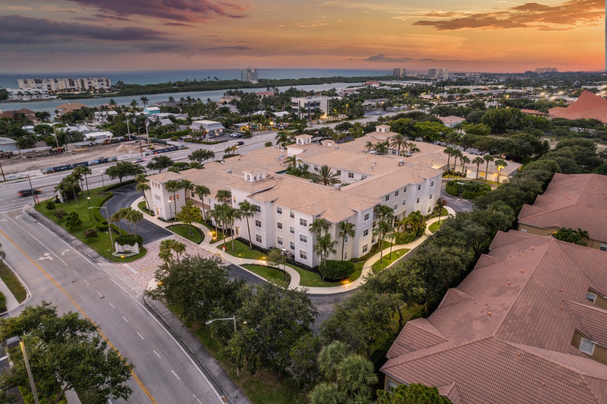 Aerial view of a residential complex surrounded by lush greenery at sunset.