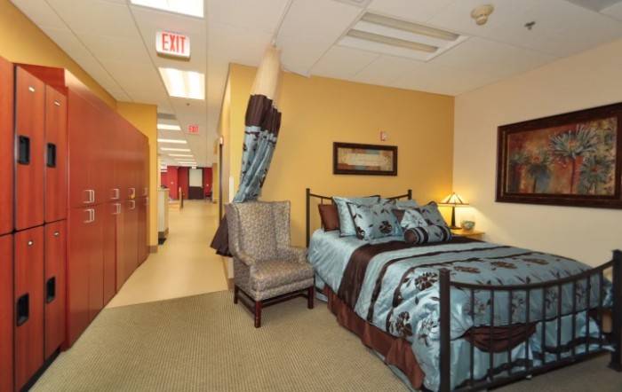 A cozy bedroom setup with a bed, chair, and decorative elements in a hallway setting.