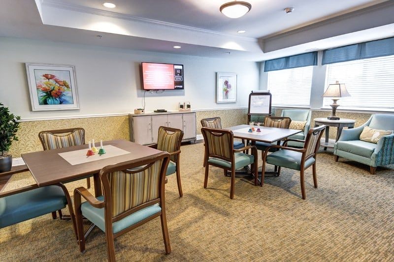 A comfortable room with tables and chairs, a television, and decorative artwork.