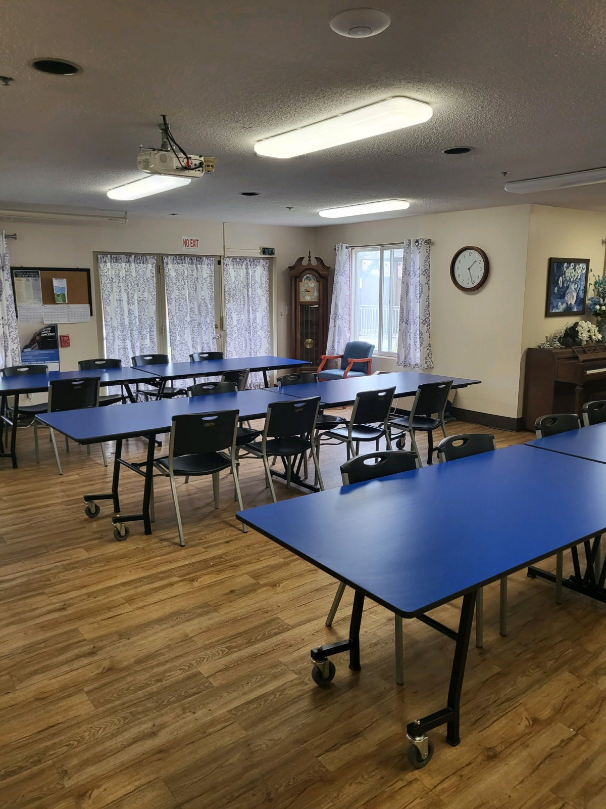 An empty classroom with blue tables and chairs arranged in rows.