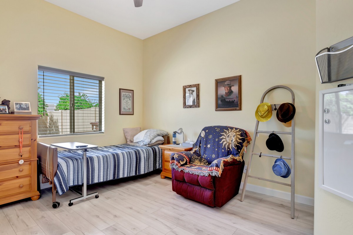 A cozy bedroom featuring a single bed, armchair, and wall decorations.
