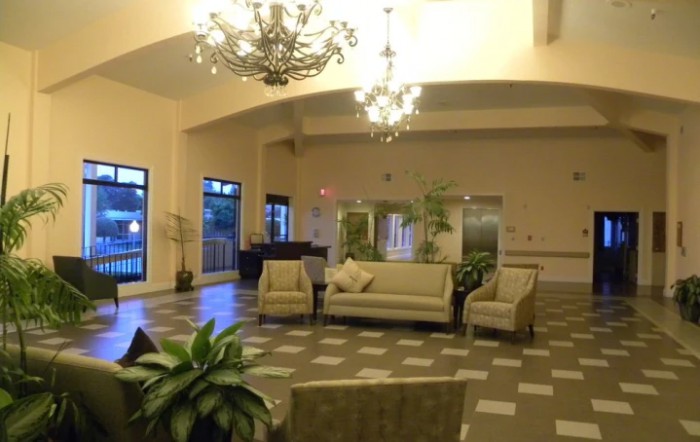 A spacious lobby area featuring elegant chandeliers, comfortable sofas and chairs, and decorative plants.
