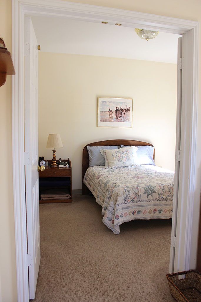 A cozy bedroom with a decorative bedspread and a nightstand with a lamp.