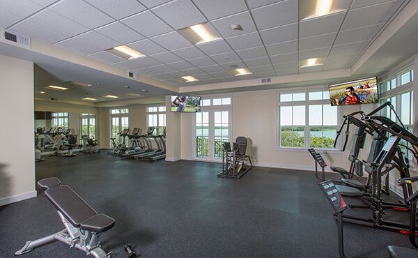 A modern gym with large windows and a variety of exercise equipment.