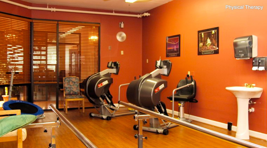 A rehabilitation room equipped with exercise machines and parallel bars for physical therapy.