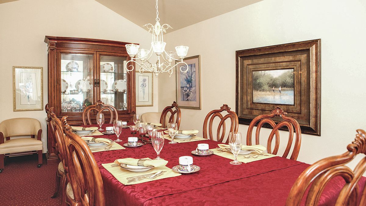 An elegantly decorated dining room with a red tablecloth and fine china set for a meal.