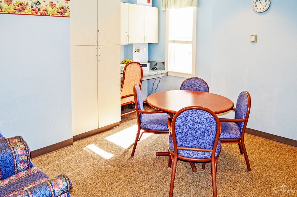 A small meeting room with a round table surrounded by blue chairs and storage cabinets.