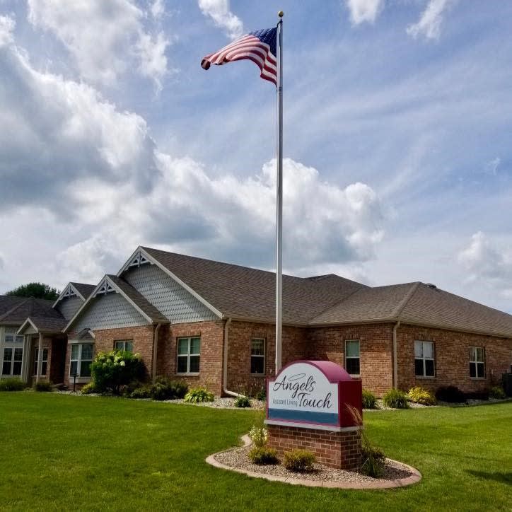 A brick building with a flagpole and sign in front, set against a cloudy sky.