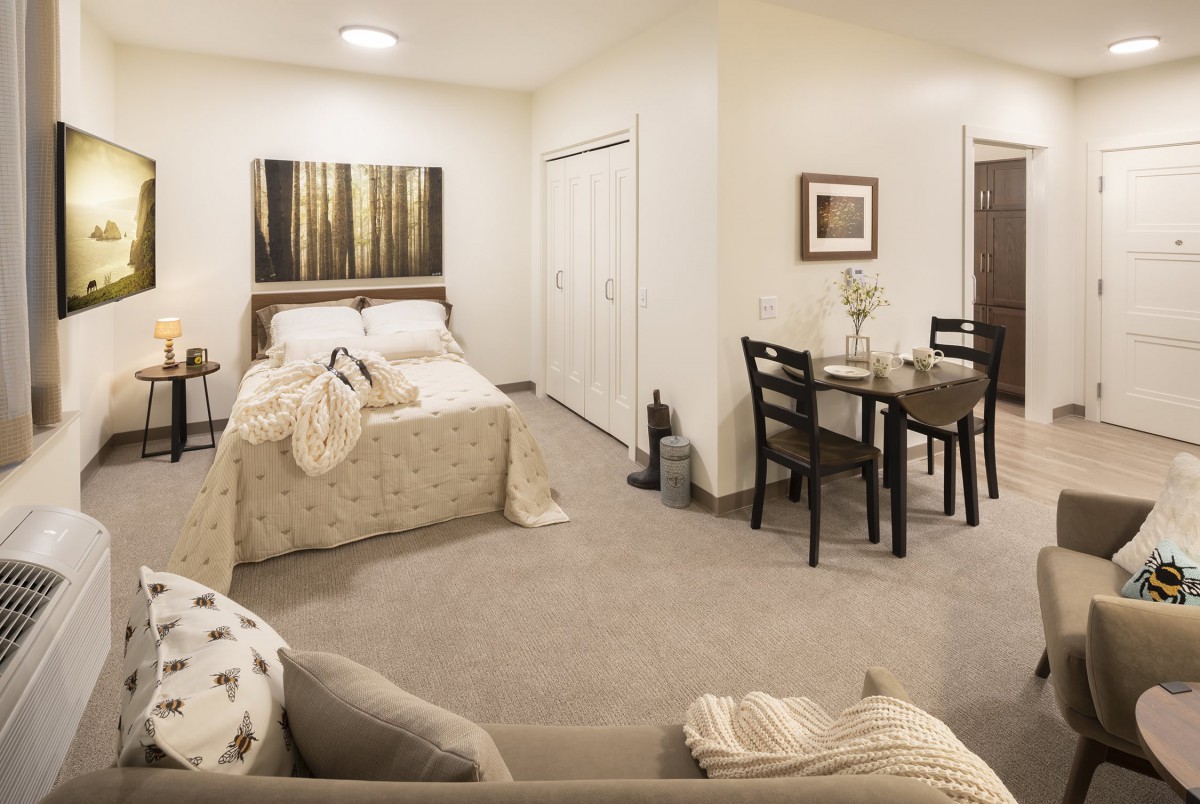 A cozy studio apartment with a combined bedroom, dining area, and living space decorated in neutral tones.