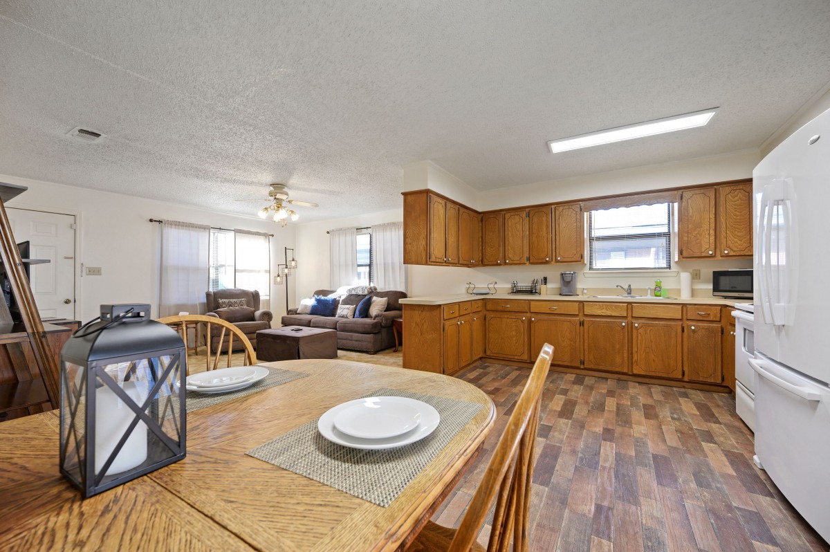 An open-concept kitchen and living area with wood cabinets and flooring.