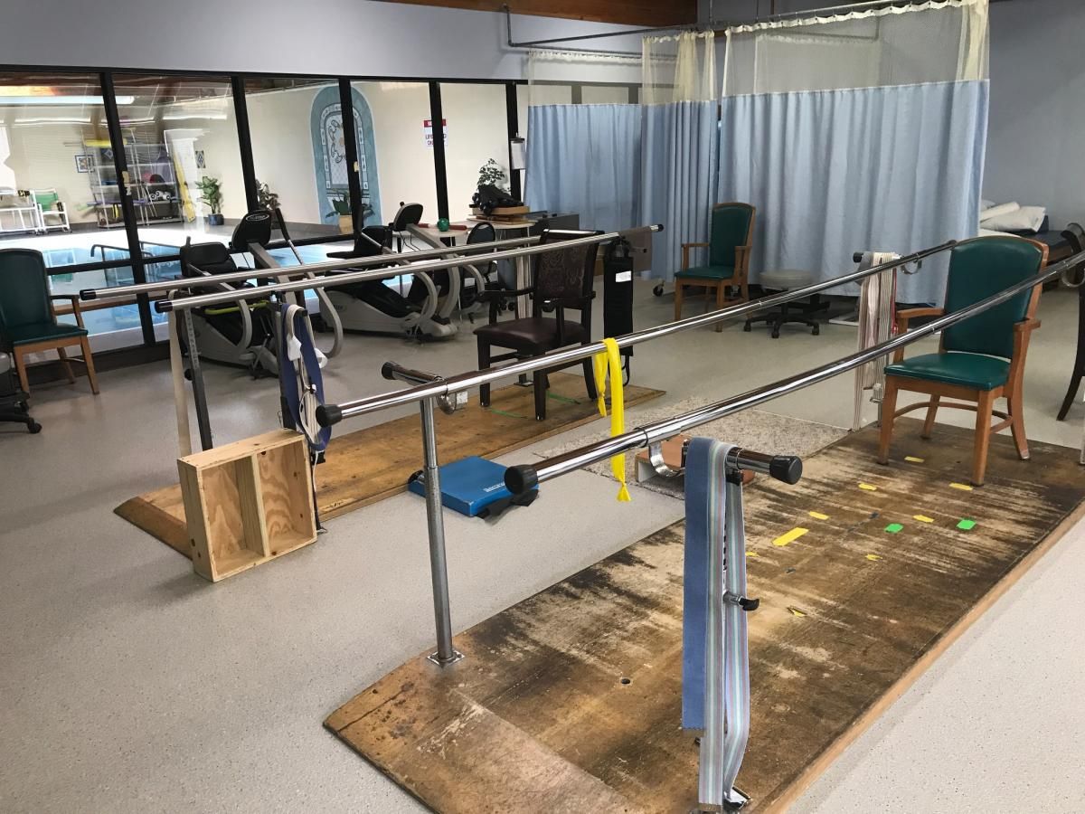 A rehabilitation gym with parallel bars and exercise equipment for physical therapy.