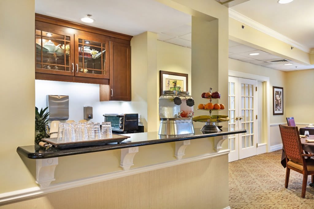 A modern kitchen interior with a counter featuring a coffee maker and fruit display.