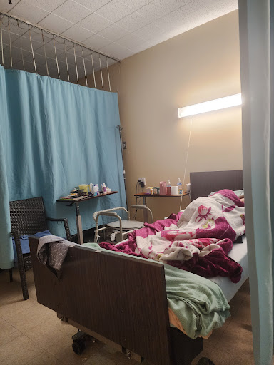A patient room in a hospital, featuring a bed with blankets and medical equipment.