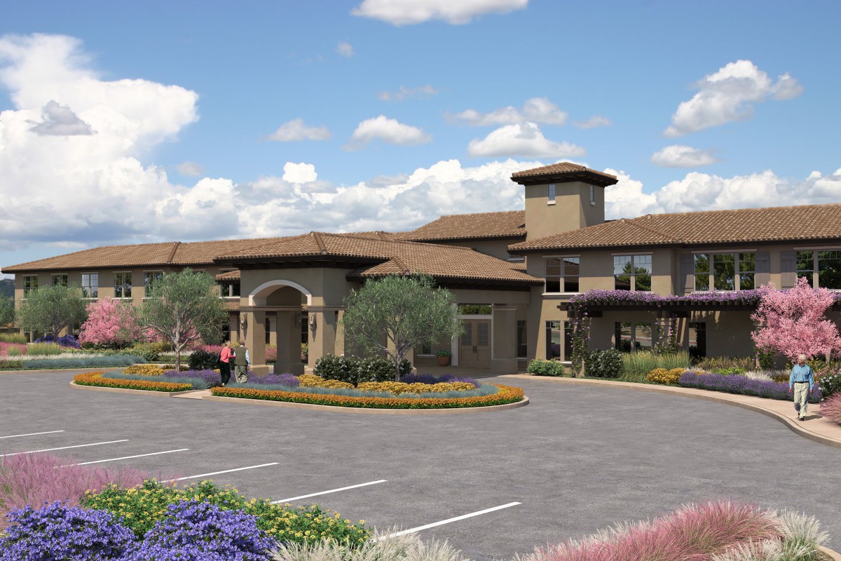 A modern building with neatly landscaped surroundings and a spacious parking lot under a partly cloudy sky.