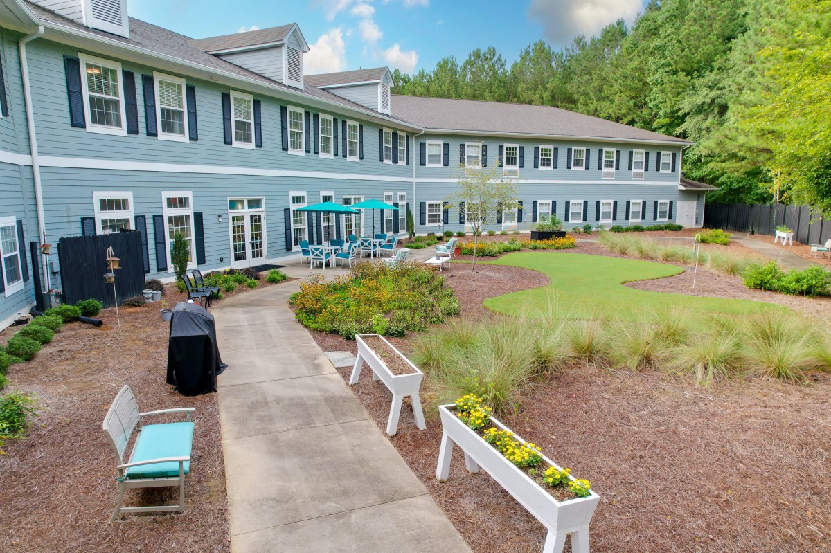 A modern residential building with landscaped gardens and outdoor seating.