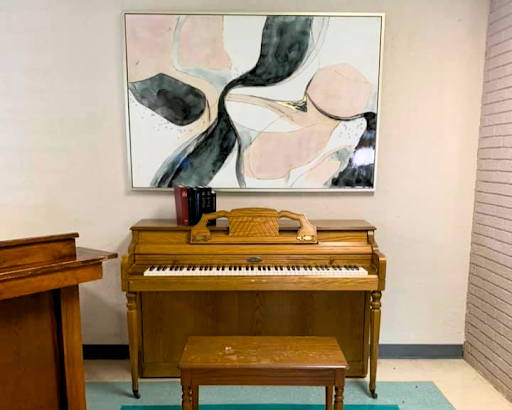 A vintage wooden piano accompanied by an abstract painting, creating a harmonious blend of music and art in the interior.