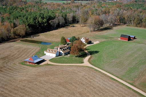 An aerial view of a tranquil rural farm surrounded by fields and autumn foliage.