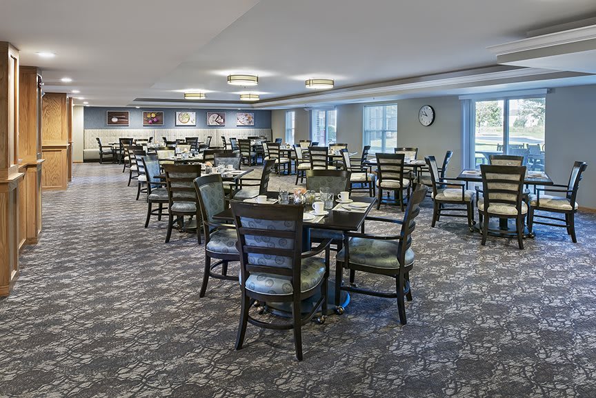 An empty dining room with neatly arranged tables and chairs, featuring modern decor and lighting.