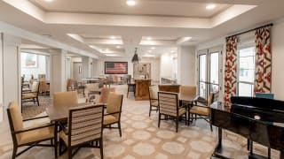 A modern dining area with neatly arranged tables and chairs, featuring elegant lighting and decor.