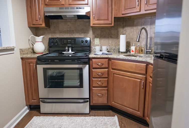 A cozy kitchen featuring wooden cabinets, a stainless steel stove and oven, and a sink with a countertop.