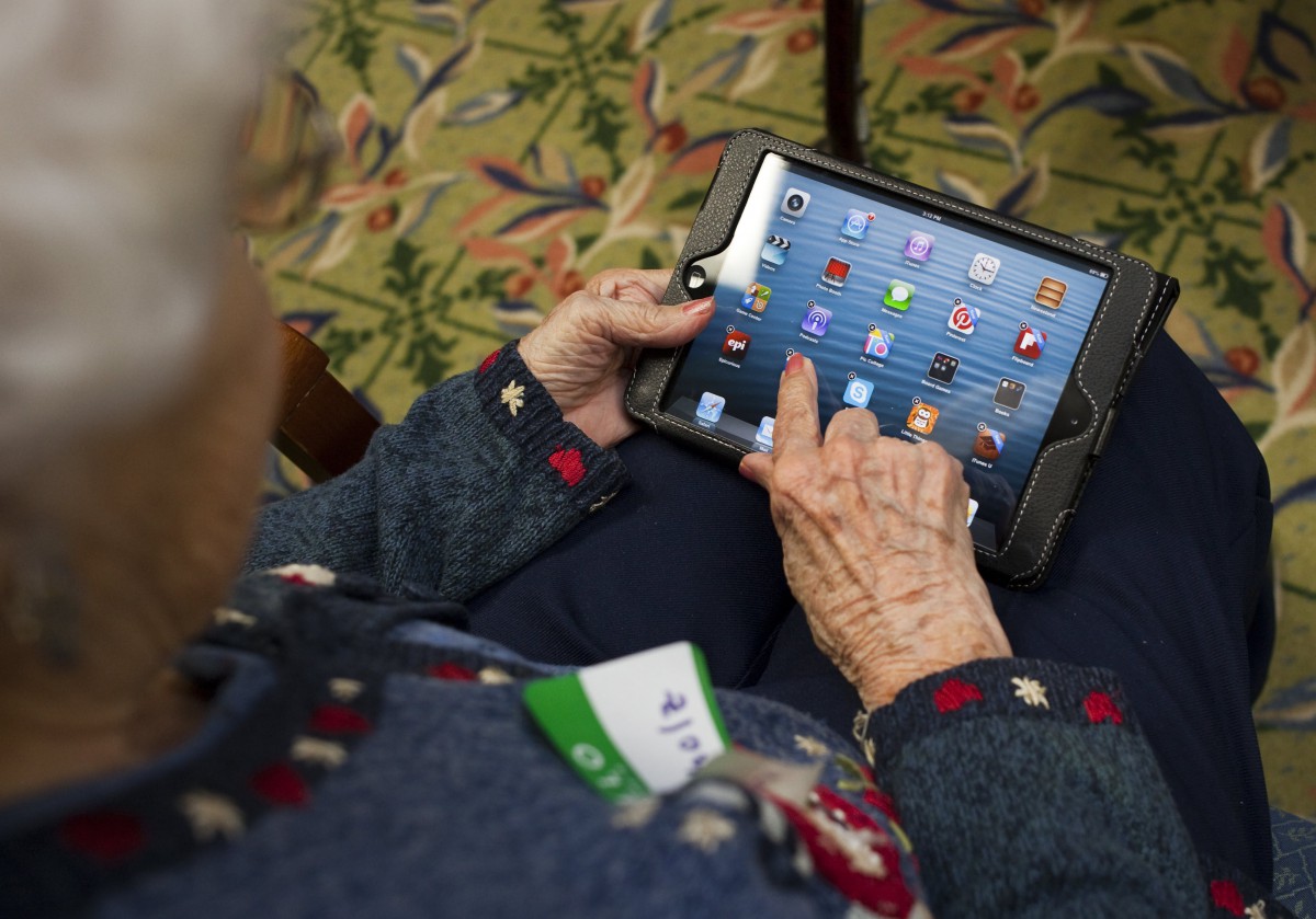 An elderly person using a tablet to navigate apps.
