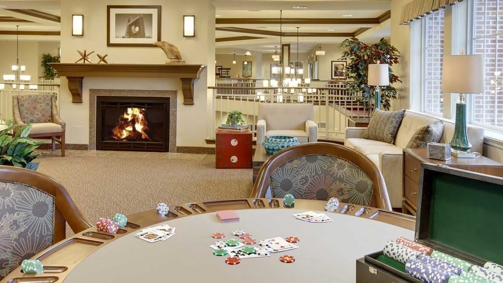 A cozy living room featuring a fireplace and a poker table set with cards and chips.