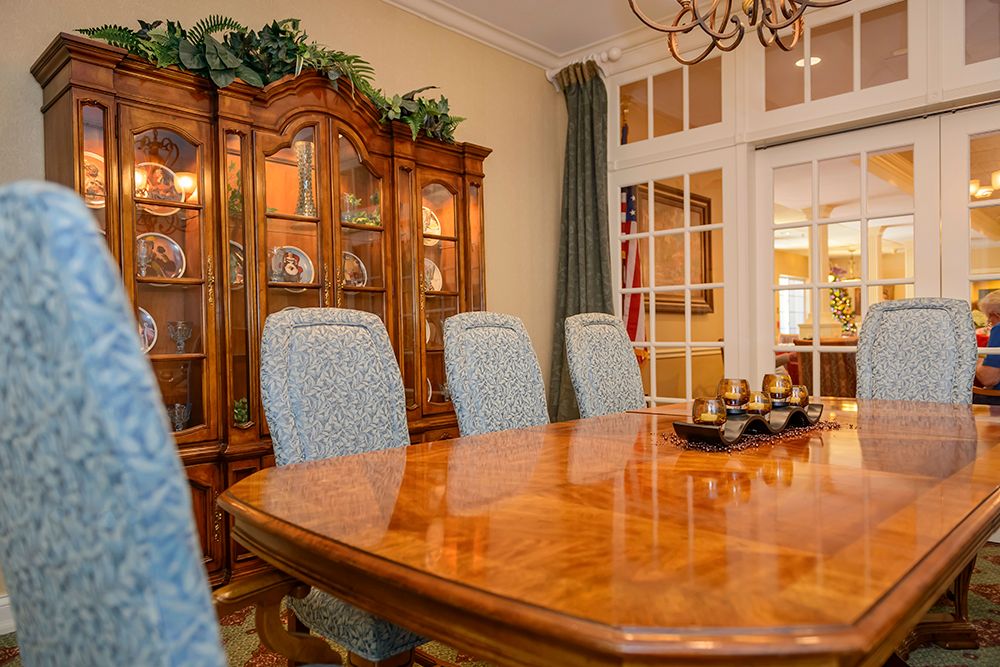 A cozy dining room with a wooden table and chairs, accompanied by a display cabinet and chandelier.