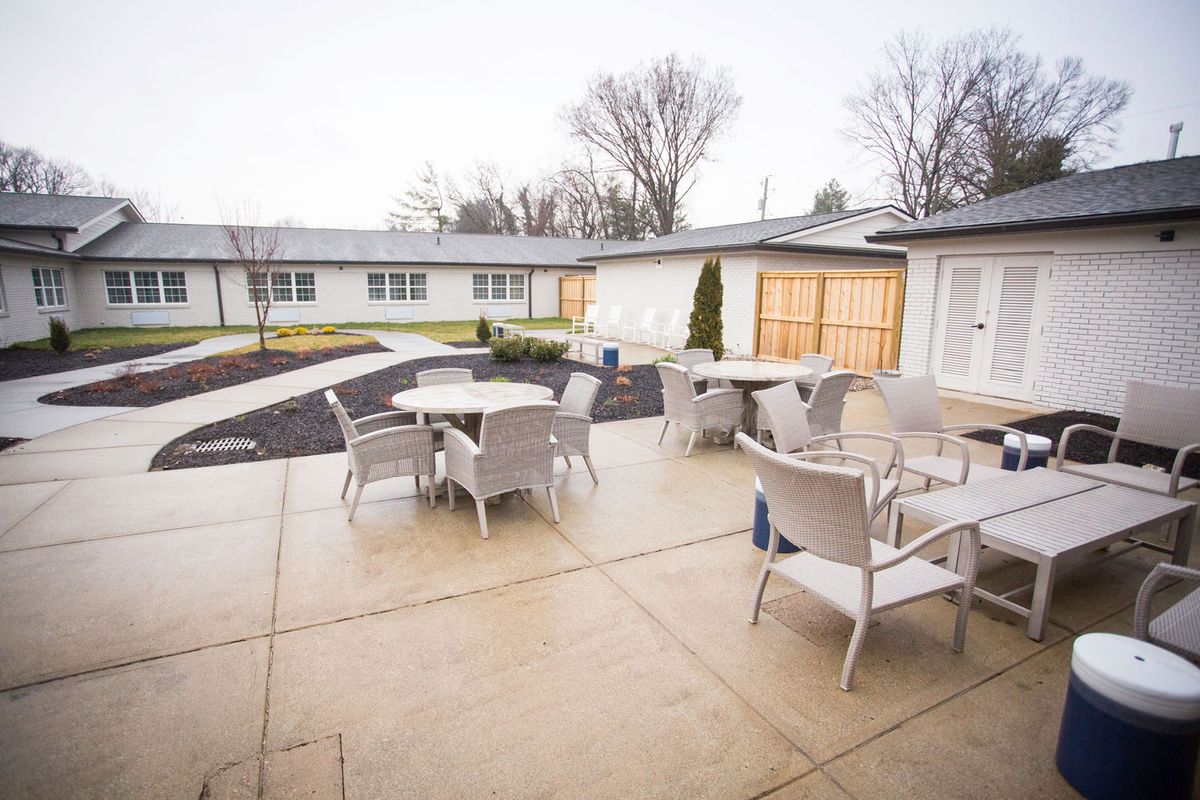 An outdoor patio area with tables and chairs on a cloudy day, surrounded by residential buildings.