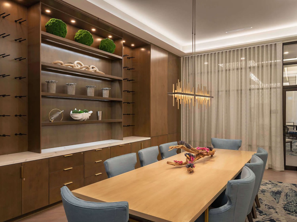 A modern dining room with a wooden table, blue chairs, and elegant lighting.