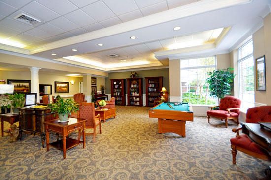 A spacious lounge with a pool table, bookshelves, and comfortable seating arrangements.