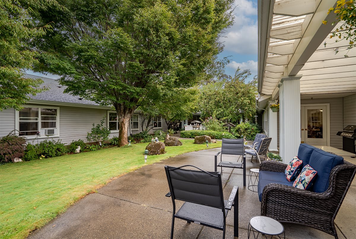 A peaceful backyard patio with chairs overlooking a lush garden.