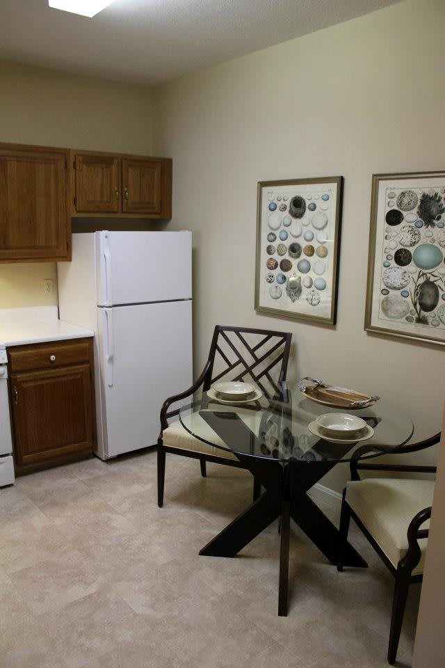 A cozy kitchen and dining area with a glass table set for two.