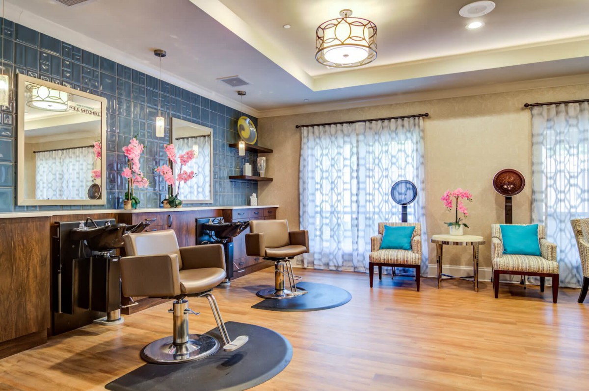 A modern and stylish hair salon interior featuring comfortable chairs, decorative mirrors, and vibrant floral accents.