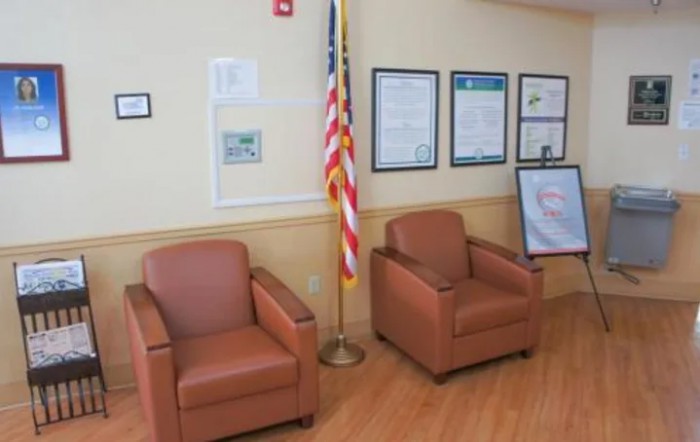 A waiting area with two chairs, an American flag, and posters on the wall.