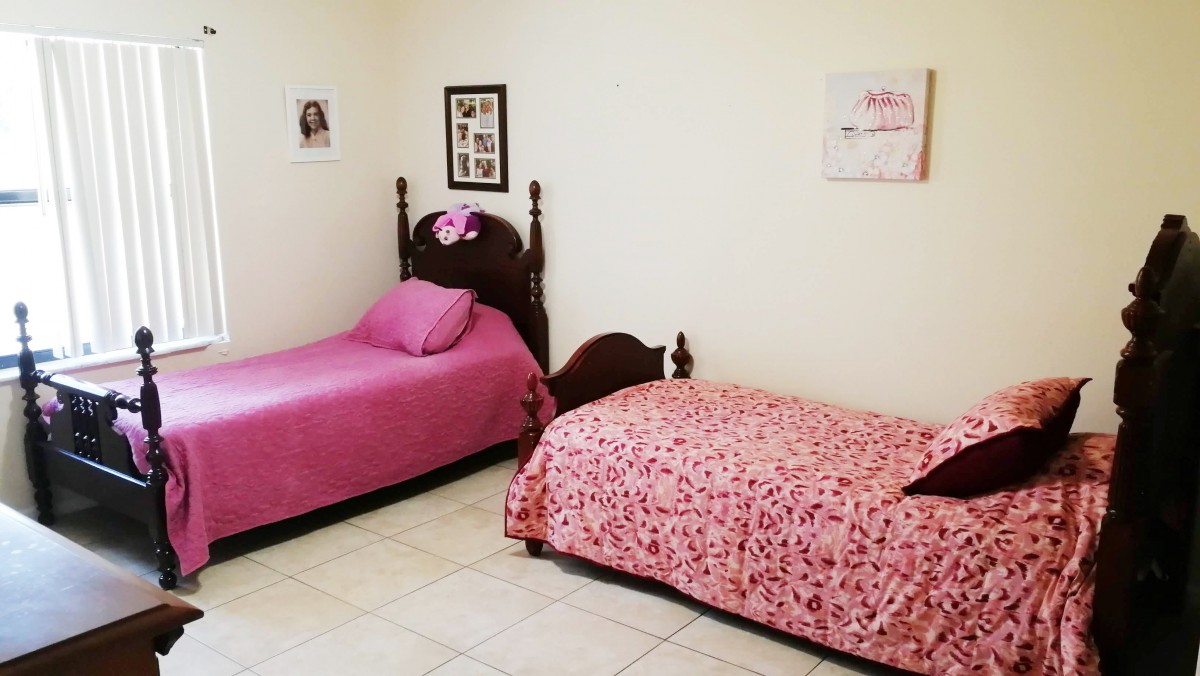 A neatly arranged bedroom with two twin beds featuring pink bedding and decorative wall art.