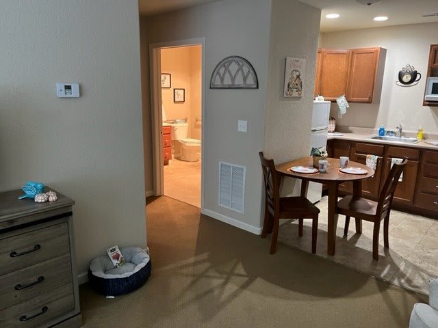 A cozy apartment featuring a dining area with a wooden table and chairs, leading into the kitchen.