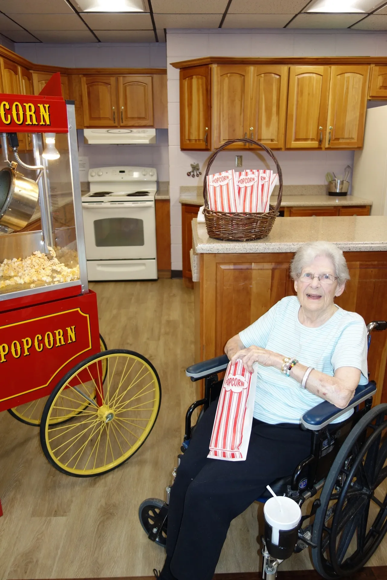 An elderly person in a wheelchair enjoying popcorn in a kitchen setting.