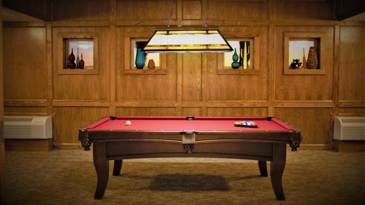 A stylish game room featuring a red-felt pool table under a hanging light, with decorative vases on wooden walls.