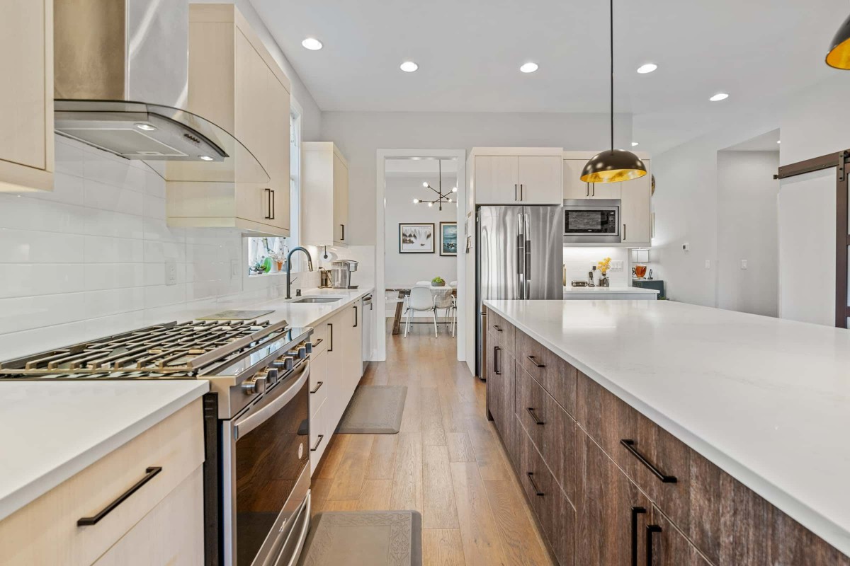 A modern kitchen featuring stainless steel appliances, wood flooring, and a central island.