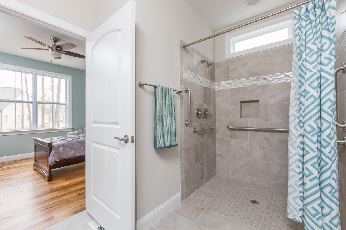A modern bathroom featuring a spacious walk-in shower with light-colored tiles and a towel hanging on the wall.