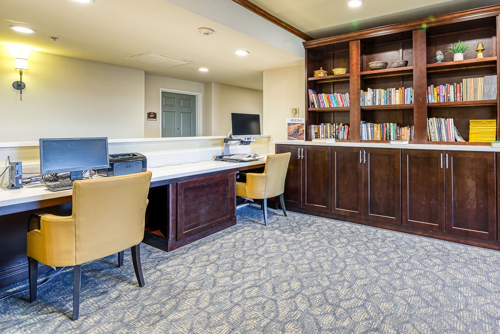A well-organized office space with desks, computers, and bookshelves filled with various books.