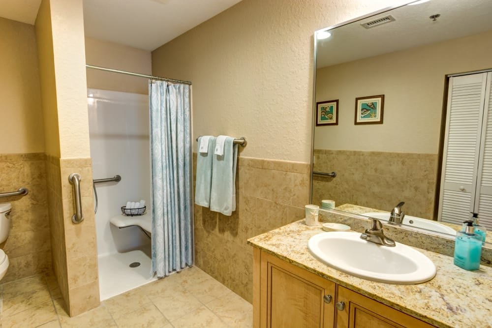 A clean and modern bathroom with a shower, sink, and mirror.