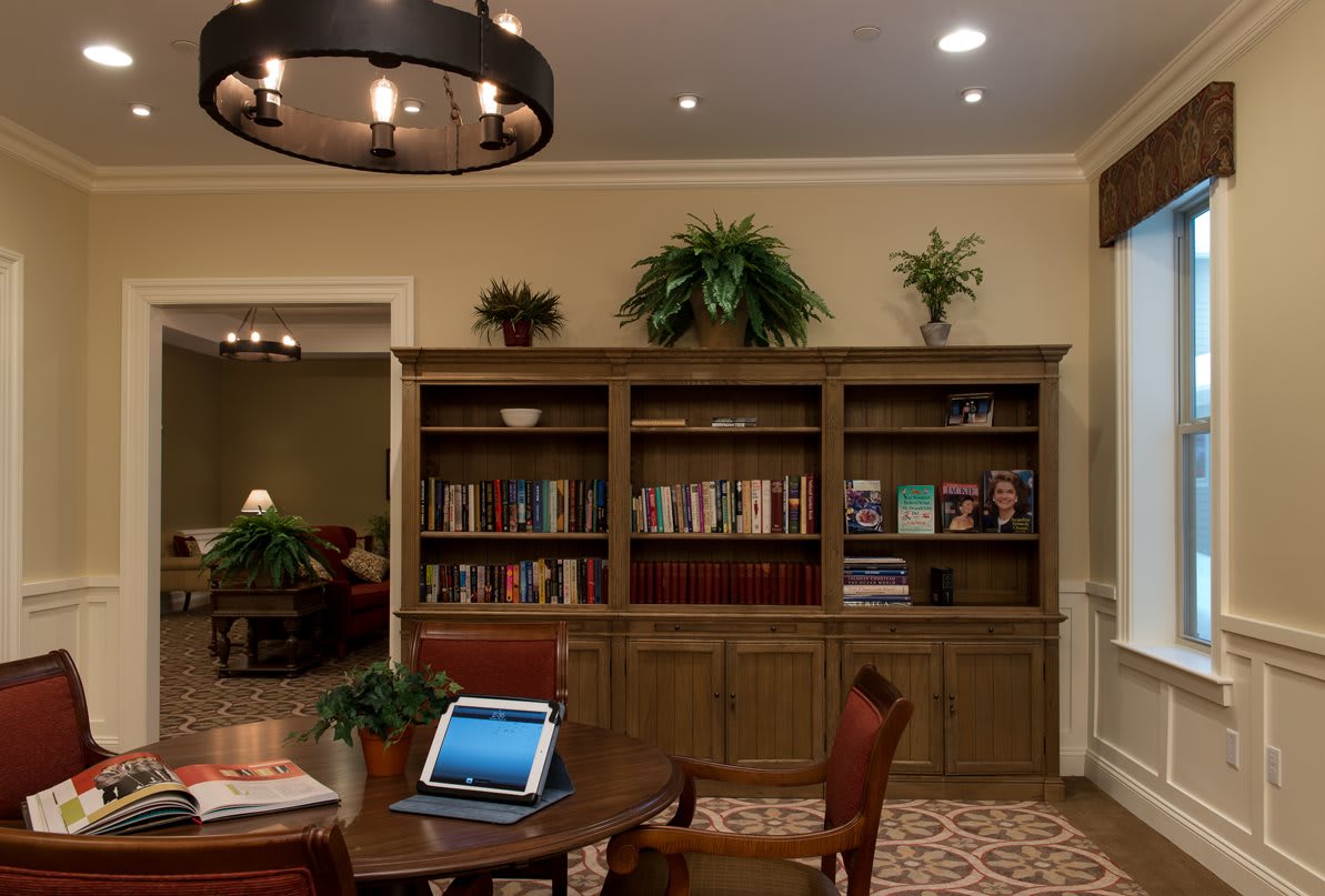 A cozy reading area with a bookshelf and a laptop on the table.