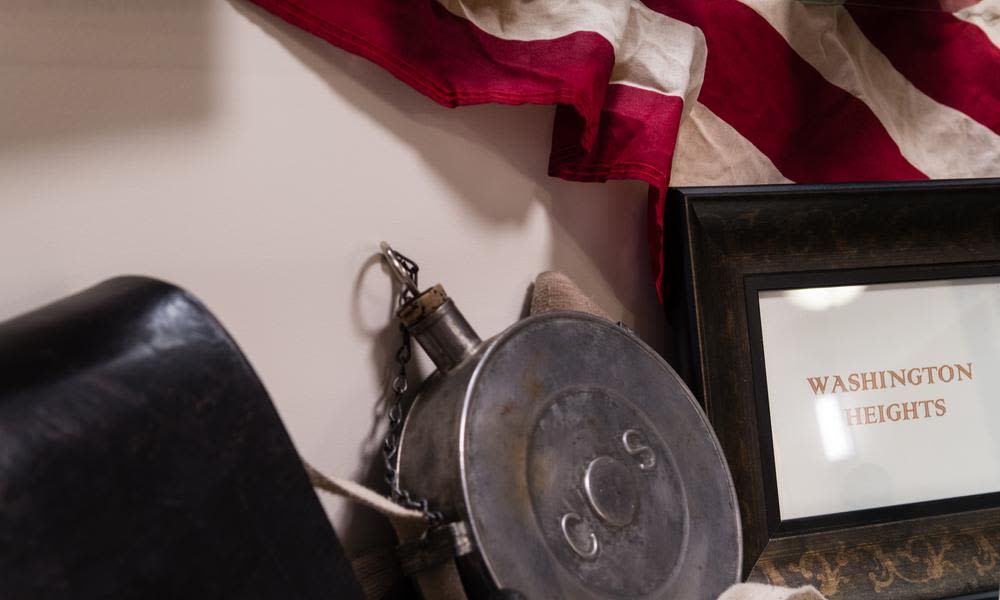 A vintage metal canteen hangs beside a flag, creating a patriotic display.